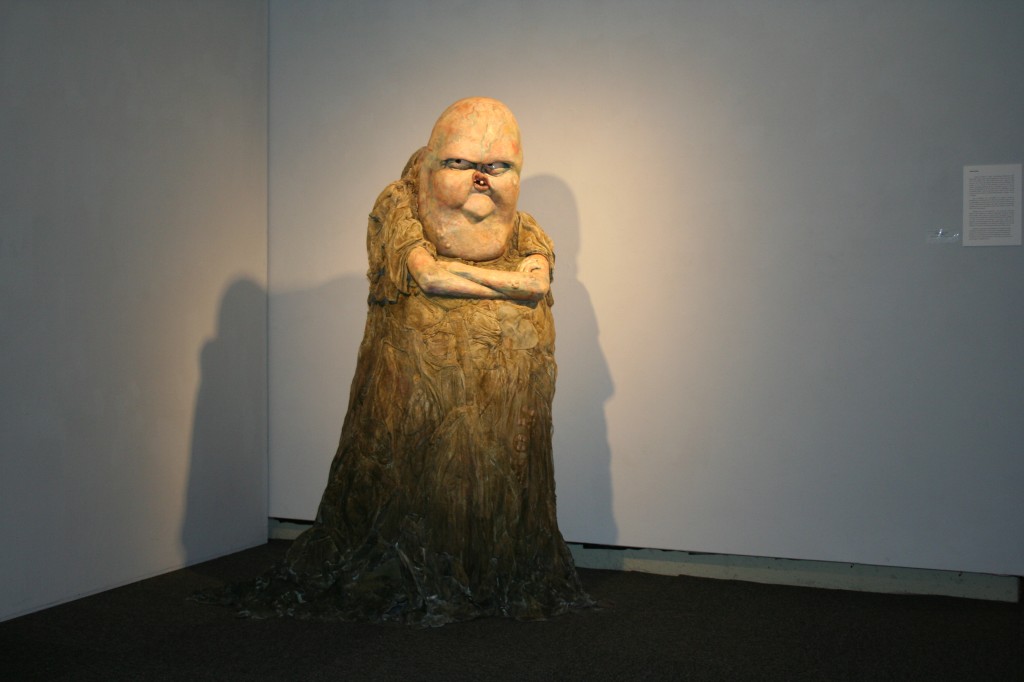sculpture of angry creature with arms crossed