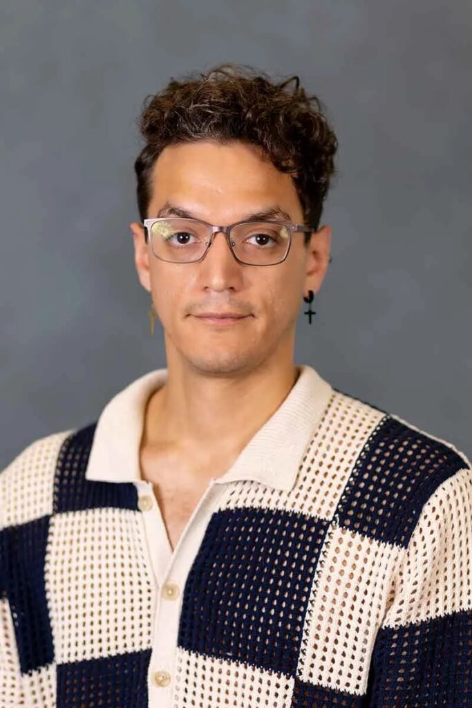 there is a man wearing glasses and a sweater posing for a picture