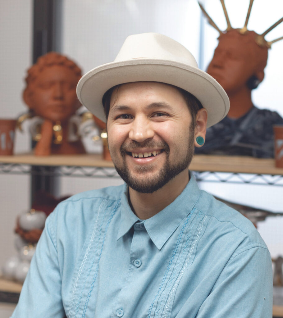 there is a man wearing a hat and smiling in front of a shelf