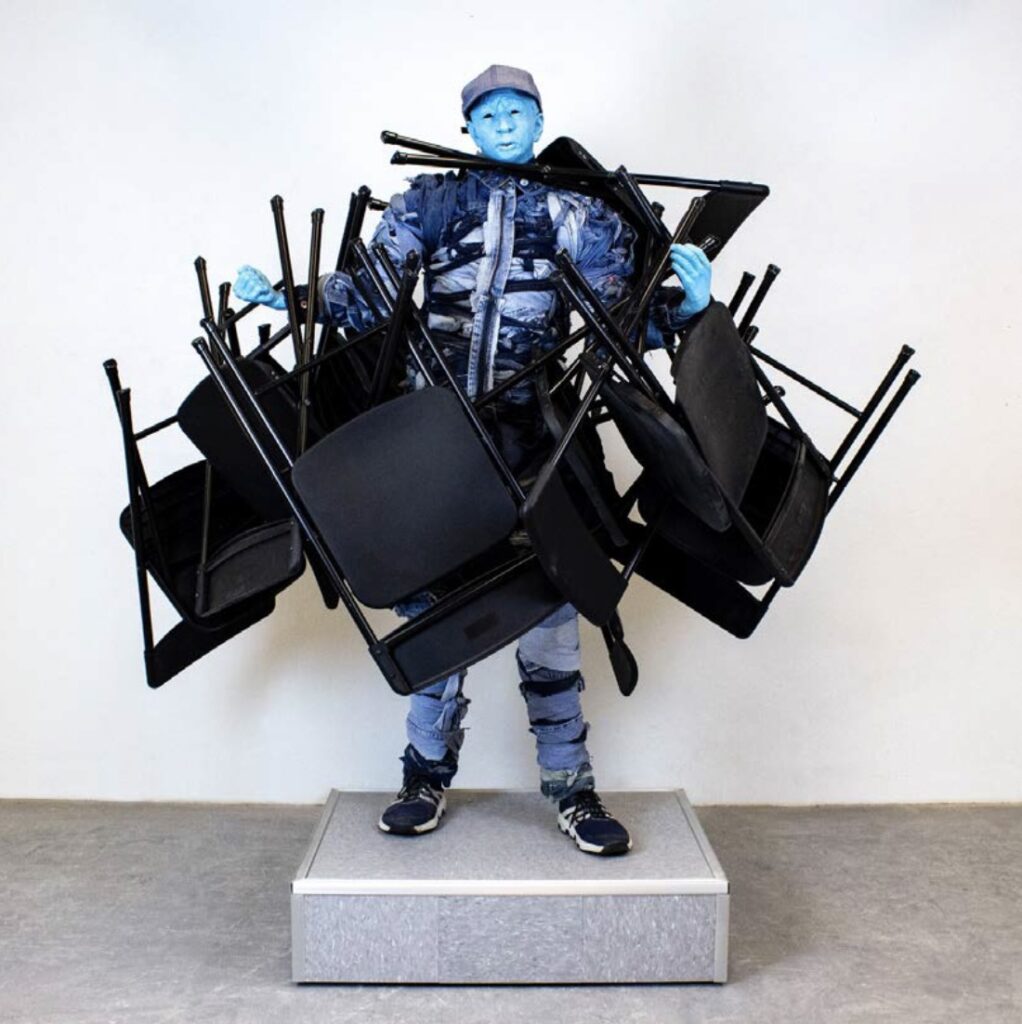 there is a statue of a man with a lot of chairs on his back
