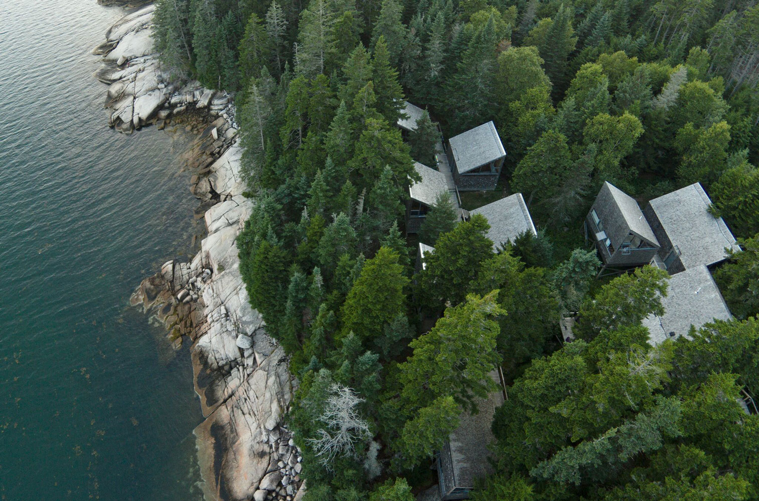 aerial view of a group of cabins sitting on the shore of a body of water