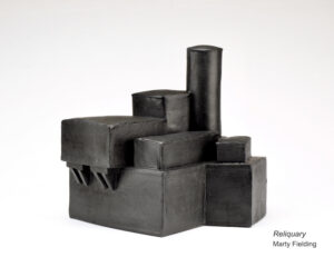 there is a black sculpture made out of concrete blocks on a white surface