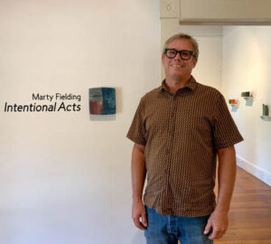 there is a man standing in front of a wall with a sign that says marty fielding international acts