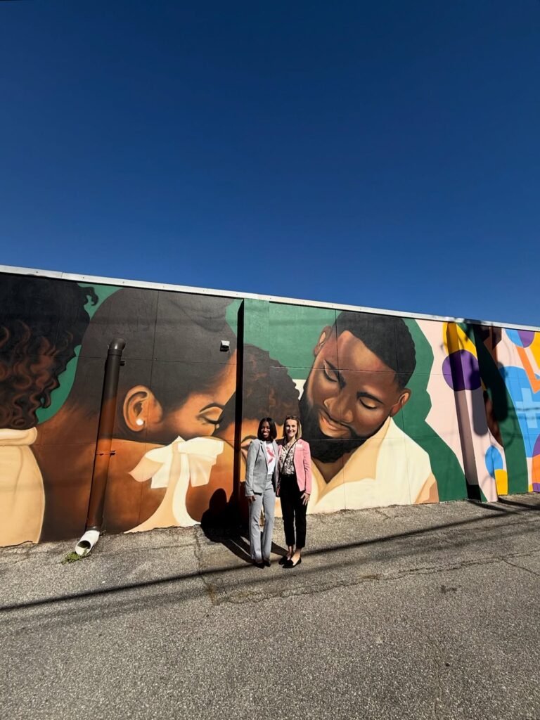 there is a man and a woman standing in front of a mural