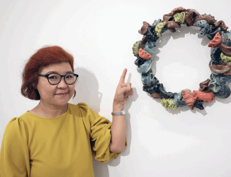 there is a woman standing next to a wall with a wreath on it