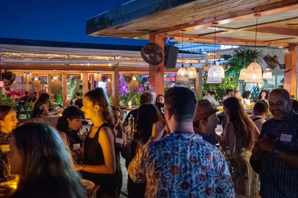 A group of people enjoying themselves at a modern rooftop bar in Miami.