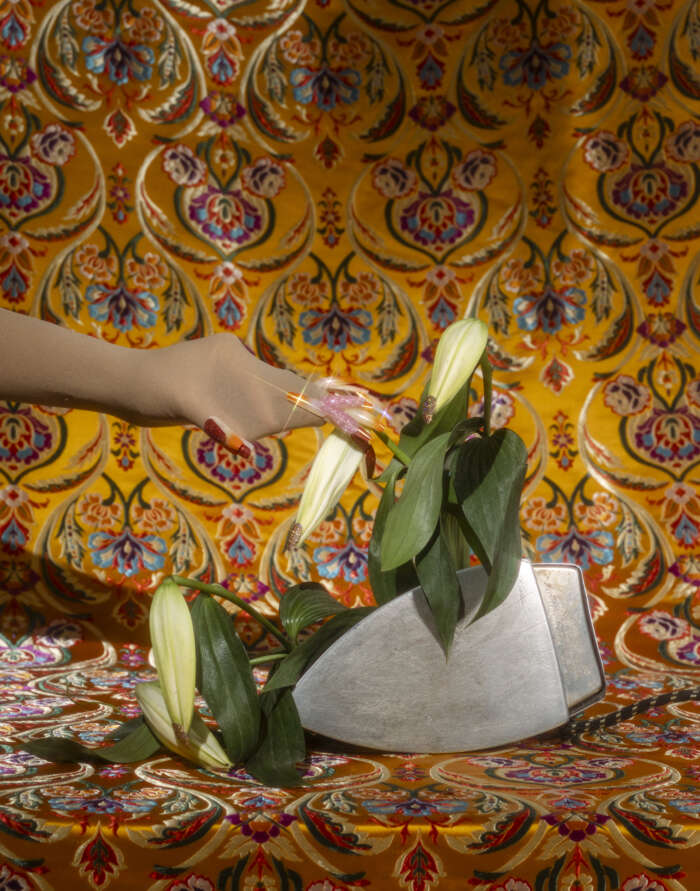 there is a person reaching for a flower in a vase on a bed
