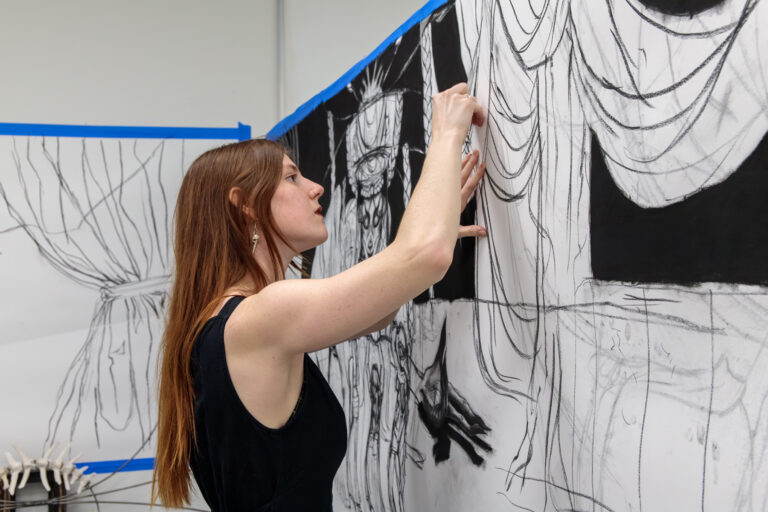a woman working on an art piece on the wall