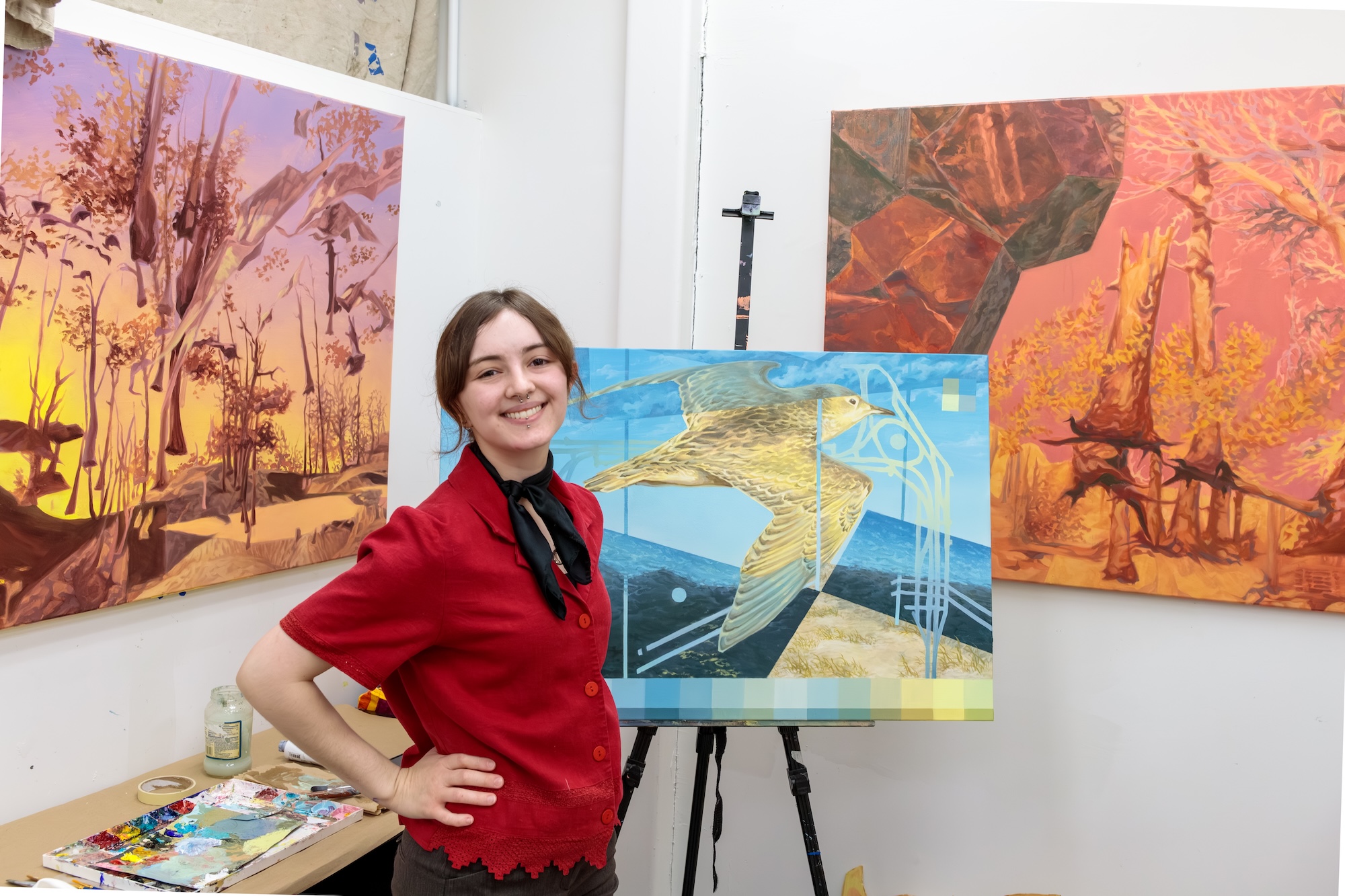 A young woman standing next to a painting of a bird