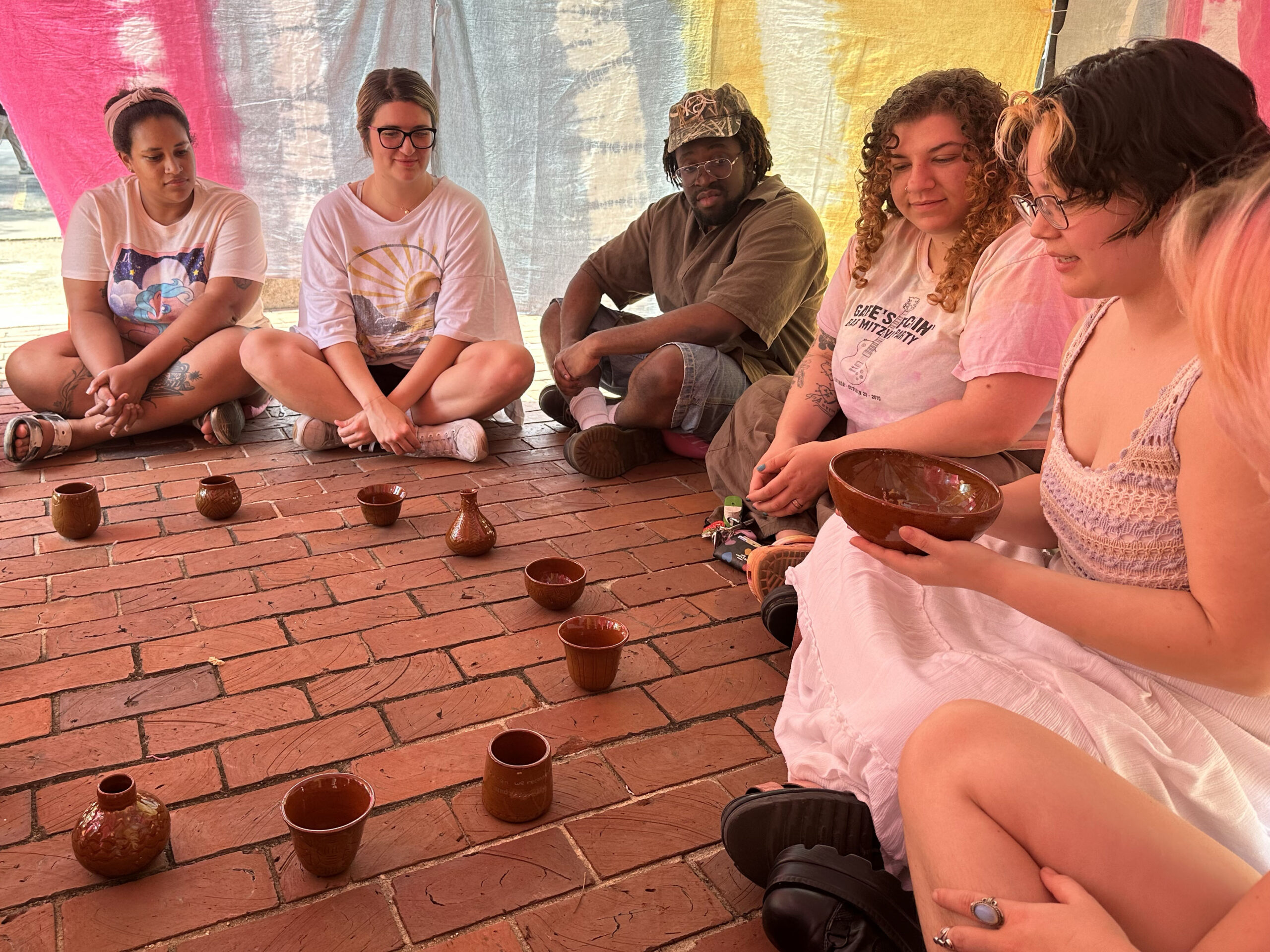 A group of people sitting with ceramic vessels